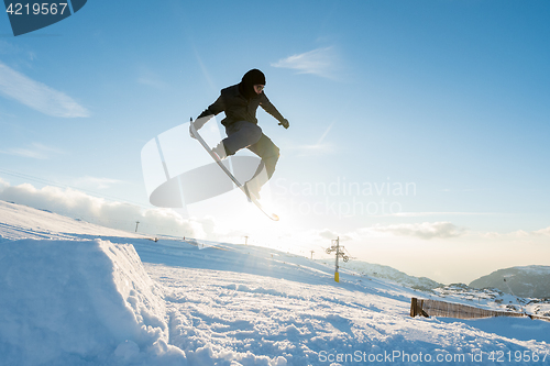 Image of Snowboarder jumping against blue sky