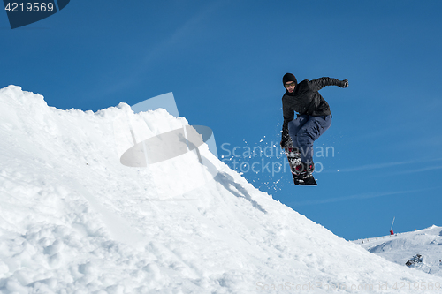 Image of Snowboarder jumping against blue sky