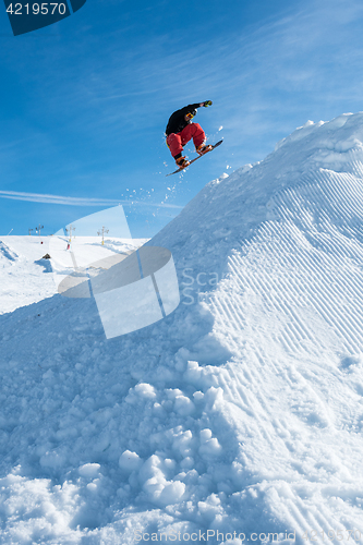 Image of Snowboarder jumping against blue sky