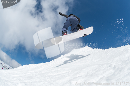 Image of Snowboarder jumping against blue sky