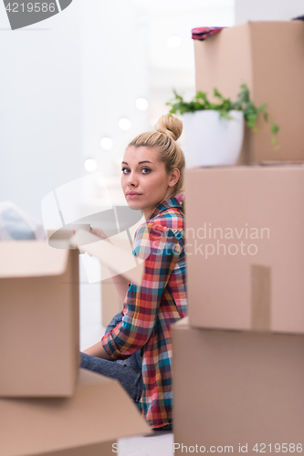 Image of woman with many cardboard boxes sitting on floor