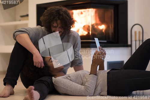 Image of multiethnic couple using tablet computer on the floor