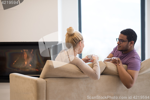 Image of Young multiethnic couple  in front of fireplace