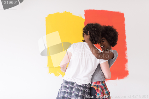 Image of multiethnic couple painting interior wall