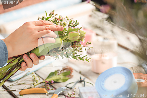 Image of Florist at work: the female hands of woman making fashion modern bouquet of different flowers