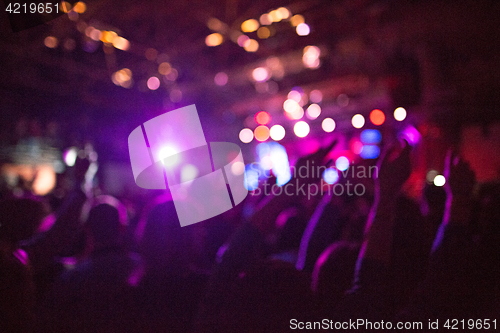 Image of The silhouettes of concert crowd in front of bright stage lights