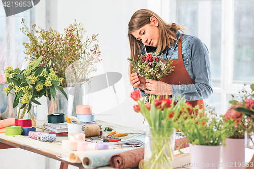 Image of Florist at work: the female hands of woman making fashion modern bouquet of different flowers