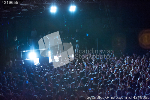 Image of The silhouettes of concert crowd in front of bright stage lights