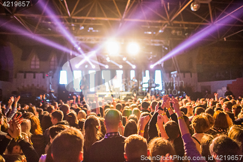 Image of The silhouettes of concert crowd in front of bright stage lights