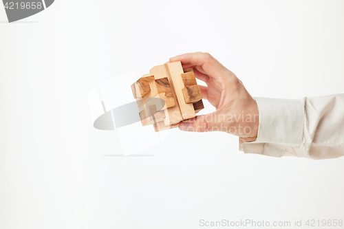 Image of Man\'s hands holding wooden puzzle.