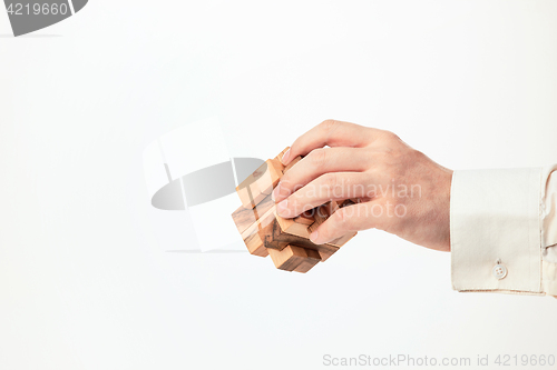 Image of Man\'s hands holding wooden puzzle.