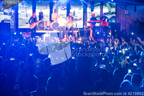 Image of The silhouettes of concert crowd in front of bright stage lights