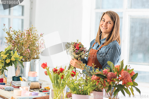 Image of Florist at work: the young girl making fashion modern bouquet of different flowers