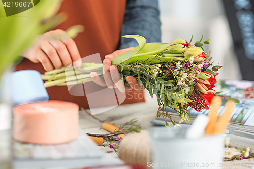 Image of Florist at work: the female hands of woman making fashion modern bouquet of different flowers