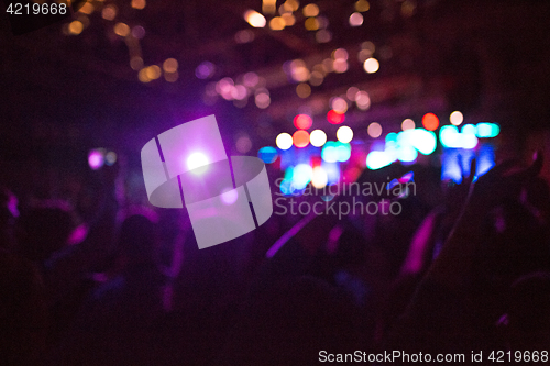 Image of The silhouettes of concert crowd in front of bright stage lights