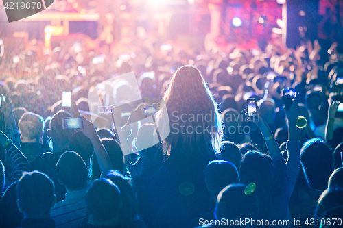 Image of The silhouettes of concert crowd in front of bright stage lights