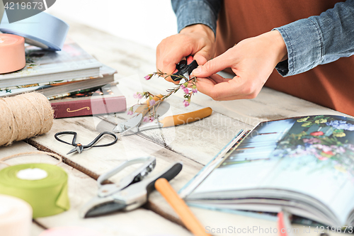 Image of Florist at work: the female hands of woman making fashion modern bouquet of different flowers