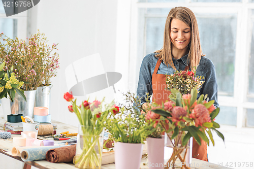 Image of Florist at work: the female hands of woman making fashion modern bouquet of different flowers