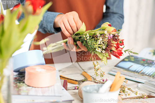 Image of Florist at work: the female hands of woman making fashion modern bouquet of different flowers