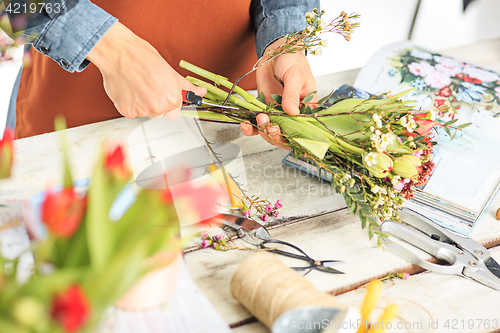 Image of Florist at work: the female hands of woman making fashion modern bouquet of different flowers