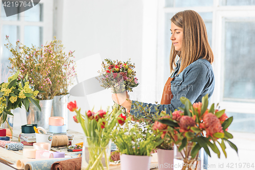 Image of Florist at work: the young girl making fashion modern bouquet of different flowers