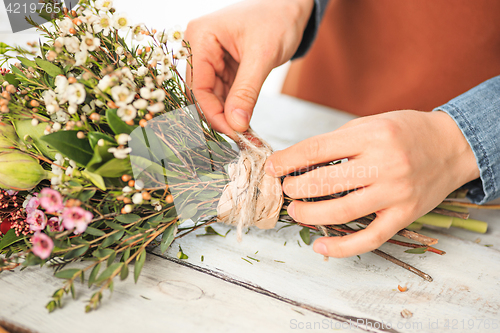 Image of Florist at work: the female hands of woman making fashion modern bouquet of different flowers
