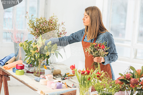 Image of Florist at work: the young girl making fashion modern bouquet of different flowers