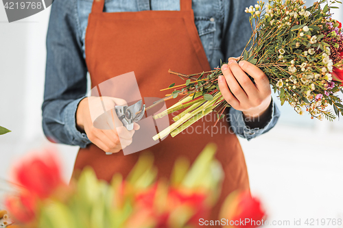 Image of Florist at work: the female hands of woman making fashion modern bouquet of different flowers