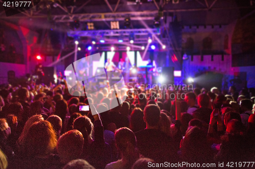 Image of The silhouettes of concert crowd in front of bright stage lights