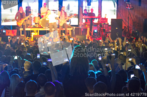 Image of The silhouettes of concert crowd in front of bright stage lights