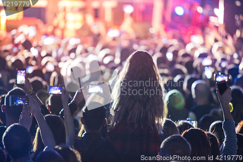 Image of The silhouettes of concert crowd in front of bright stage lights