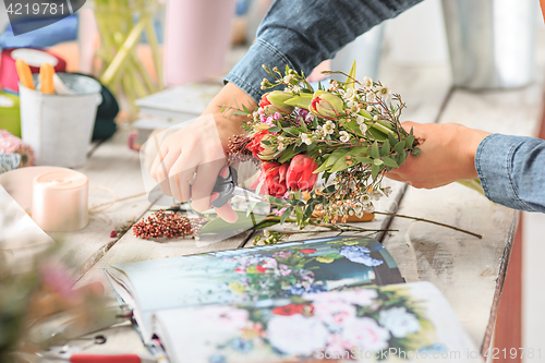 Image of Florist at work: the female hands of woman making fashion modern bouquet of different flowers