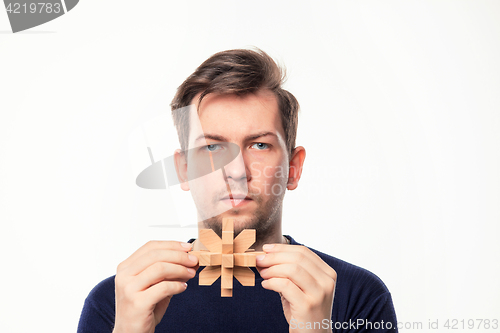 Image of Attractive 25 year old business man looking confused with wooden puzzle.