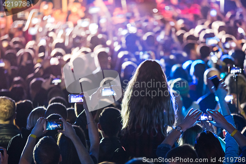 Image of The silhouettes of concert crowd in front of bright stage lights