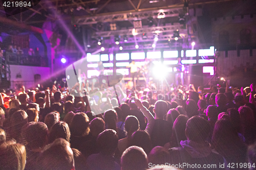 Image of The silhouettes of concert crowd in front of bright stage lights