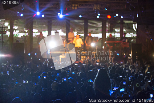 Image of The silhouettes of concert crowd in front of bright stage lights