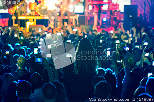 Image of The silhouettes of concert crowd in front of bright stage lights