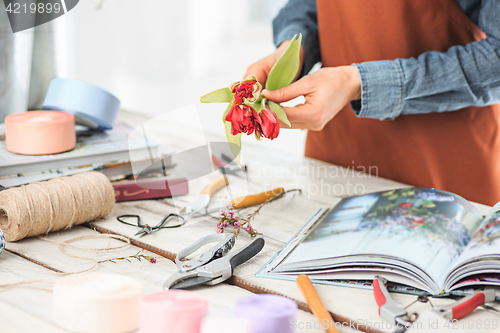 Image of Florist at work: the female hands of woman making fashion modern bouquet of different flowers