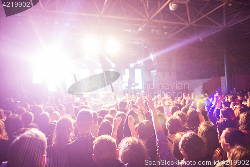 Image of The silhouettes of concert crowd in front of bright stage lights