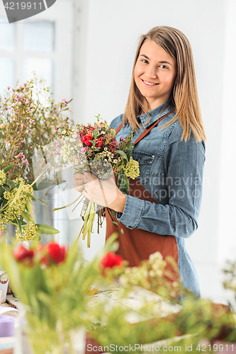 Image of Florist at work: the young girl making fashion modern bouquet of different flowers