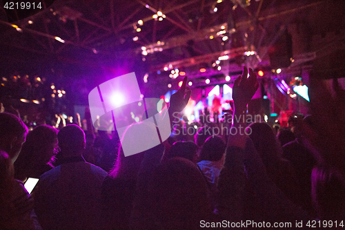 Image of The silhouettes of concert crowd in front of bright stage lights