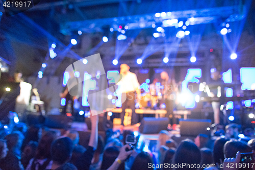 Image of The silhouettes of concert crowd in front of bright stage lights