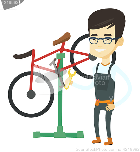 Image of Asian bicycle mechanic working in repair shop.