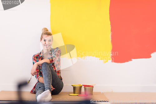 Image of young female painter sitting on floor