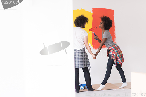 Image of multiethnic couple painting interior wall