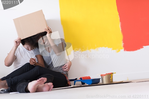 Image of young multiethnic couple playing with cardboard boxes