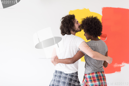 Image of multiethnic couple painting interior wall