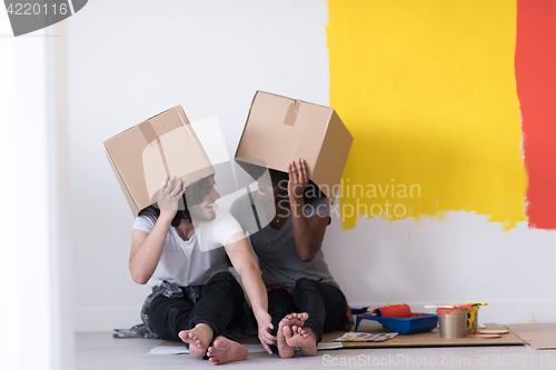 Image of young multiethnic couple playing with cardboard boxes