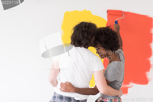 Image of multiethnic couple painting interior wall