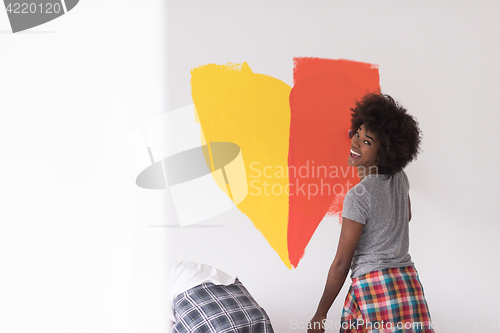 Image of multiethnic couple painting interior wall